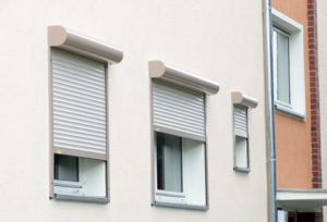 Nahaufnahme von einem weissen Haus mit heruntergelassenen silbernen Rolläden