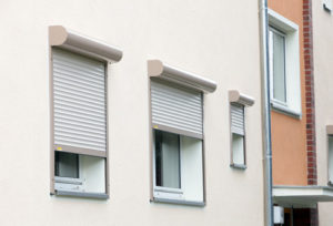 Nahaufnahme von einem weissen Haus mit heruntergelassenen silbernen Rolläden