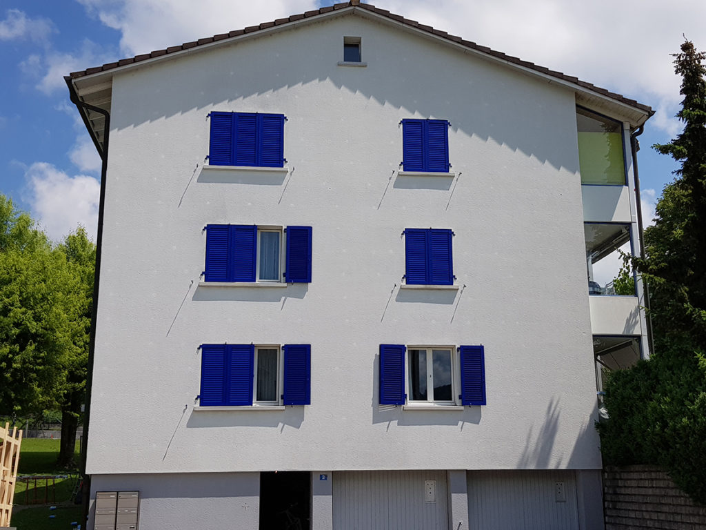 Mehrfamilienhaus mit königsblauen Fensterläden
