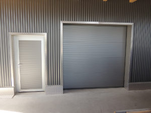 anthrazites Industrietor mit einer Eingangstür daneben