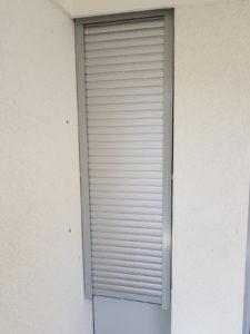 ein schmales Fenster, welches mit einer geschlossenen Rollade bedeckt ist.