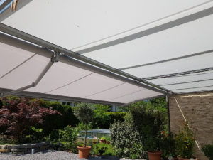 Zusehen ist der Gartenplatz von einem Einfamilienhaus in Horw, welcher von einer Sonnenstore, geschützt wird. Die Aufnahme wurde seitlich unter der Store gemacht.