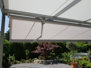 Zusehen ist der Gartenplatz von einem Einfamilienhaus in Horw, welcher von einer Sonnenstore, geschützt wird. Die Aufnahme wurde unter der Store gemacht.