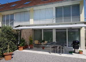 Die drei Fenster im oberen Stock des Hauses haben Lamellenstoren.